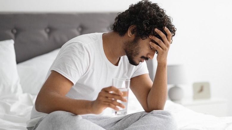 Man sitting on bed with head in hand