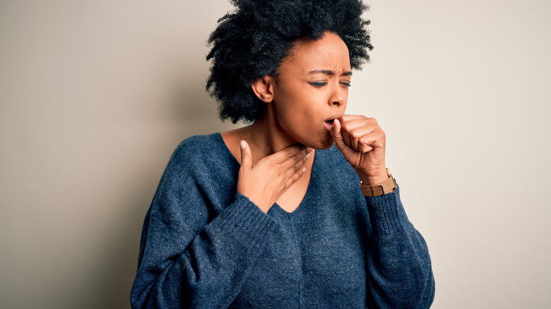 A woman coughs into her hand