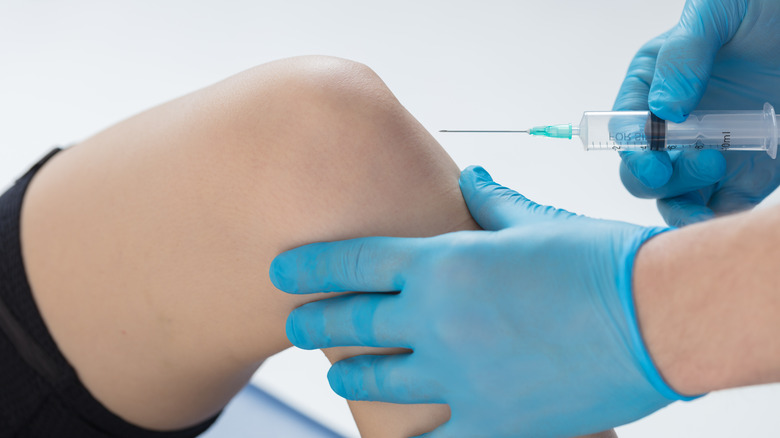 doctor pointing needle at patient's knee