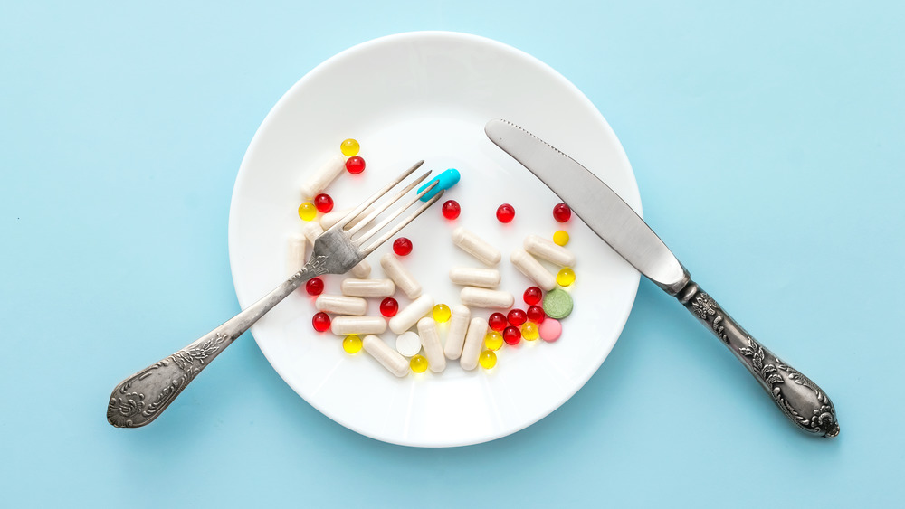 A plate holding different diet pills with a blue background 