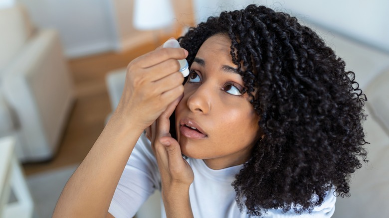 woman putting eye drops into eye