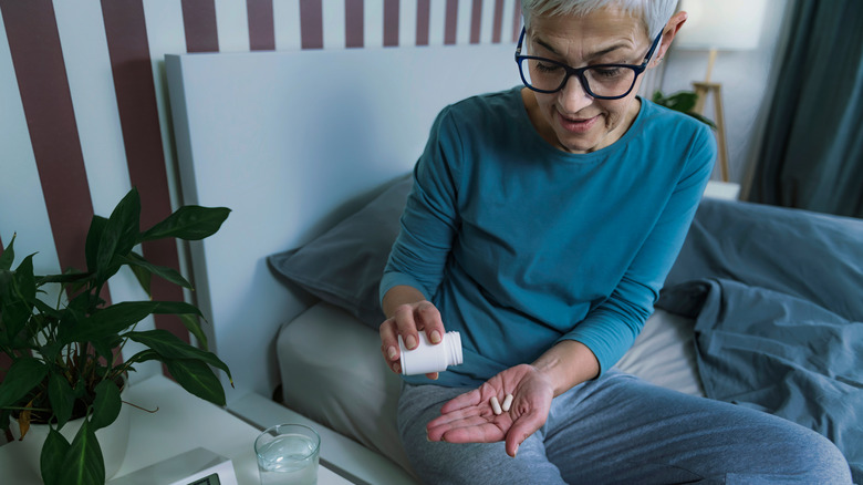 Woman pouring supplement capsules into hand