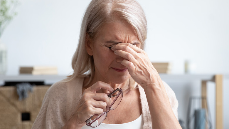 Woman rubbing eyes and holding glasses