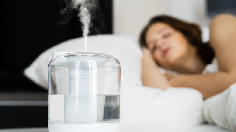 A home humidifier with a sleeping woman in background