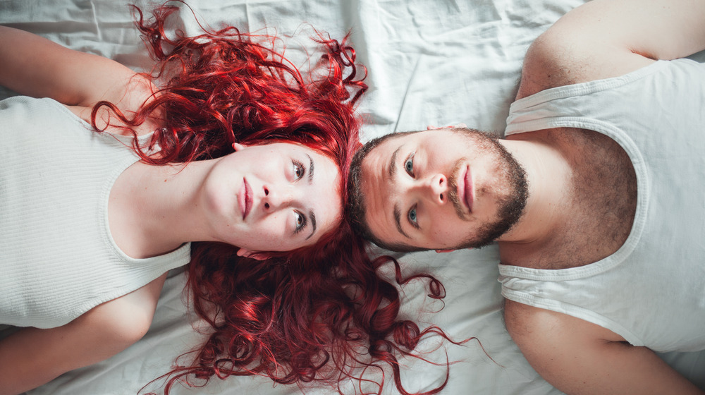 man and woman lying down with tops of heads touching