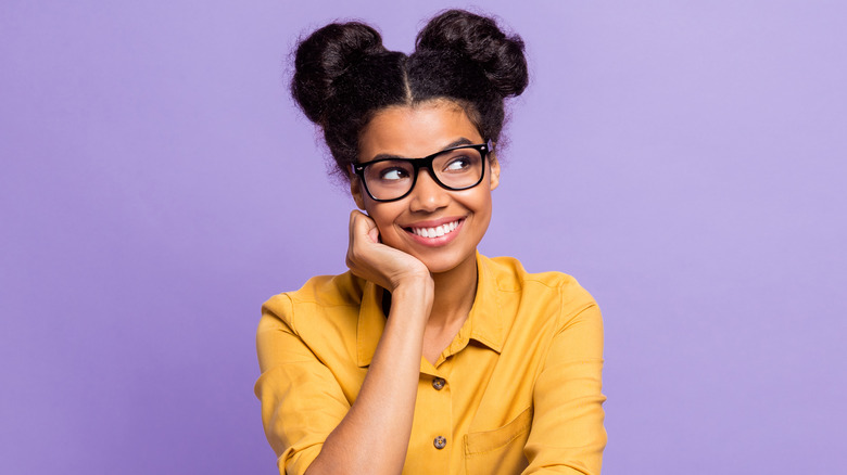Black woman with two buns thinking and smiling