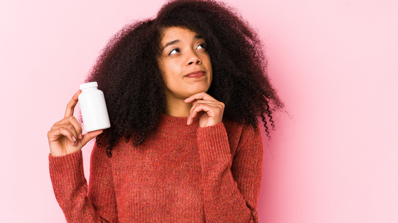 pensive woman holding pill bottle