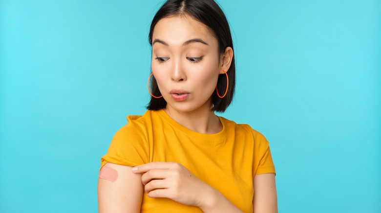 woman looks at a bandaid on her arm 