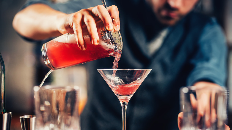 Man pouring cocktail in martini glass
