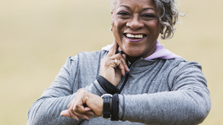 smiling older woman taking her pulse