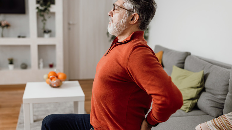 man sitting on couch stretching back