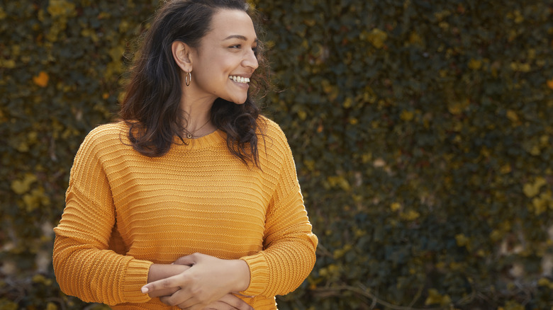 woman smiling while touching her stomach