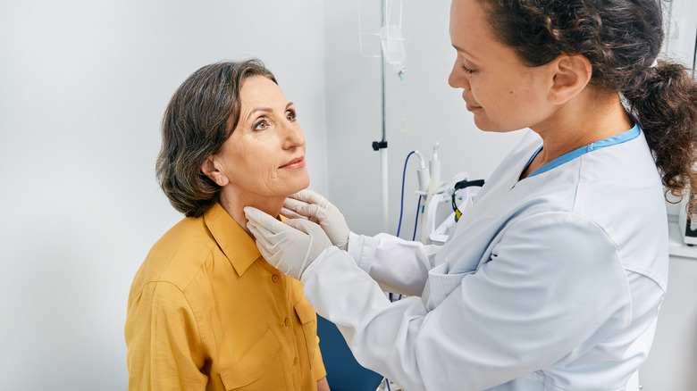 Doctor checking the thyroid of an elderly patient
