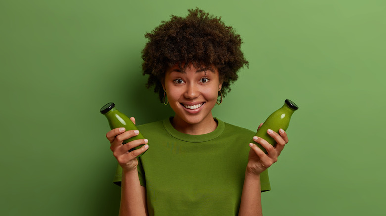 Girl holding bottles of green juice