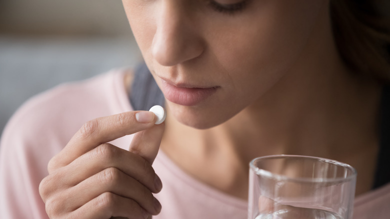 Woman lifting pill to lips