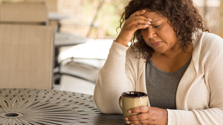 Sad woman stares into coffee mug