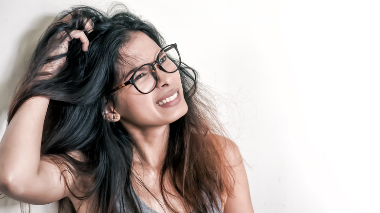 woman with long hair itching her itchy scalp 