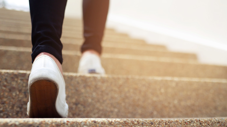 close up of a pair of legs walking up the stairs with white sneakers