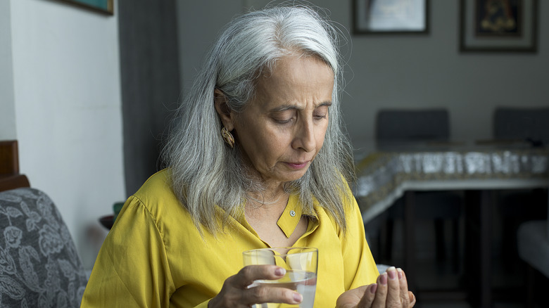 woman looking at the pills in her hand