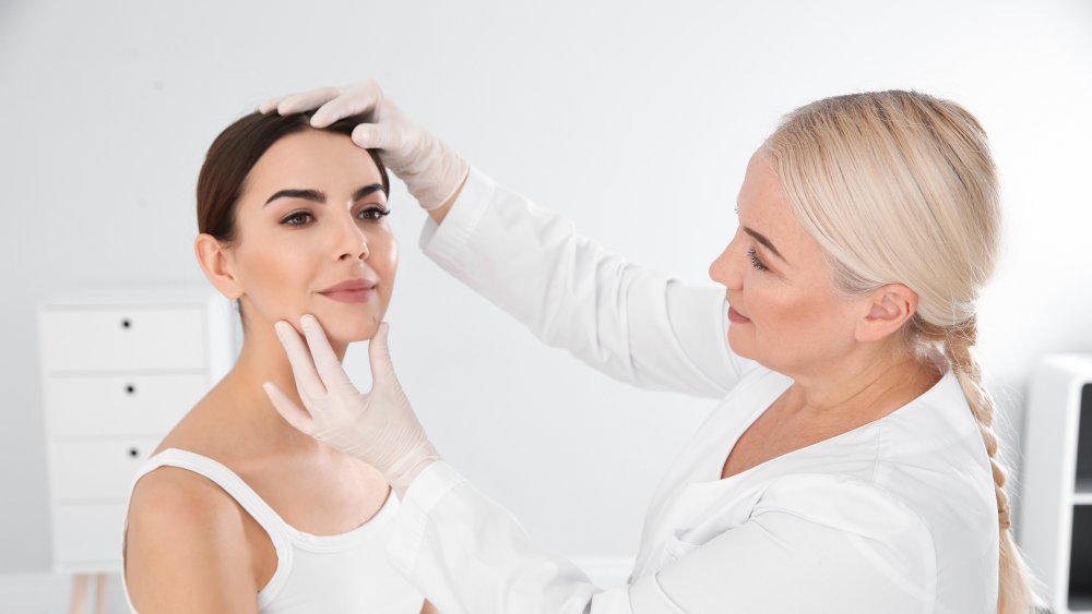 Dermatologist examining young patient's mole in clinic