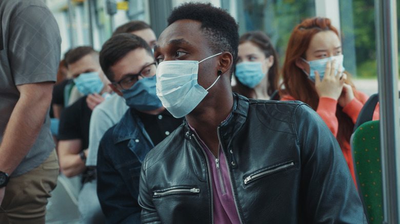 Group of passengers wearing face masks riding on a public transport bus