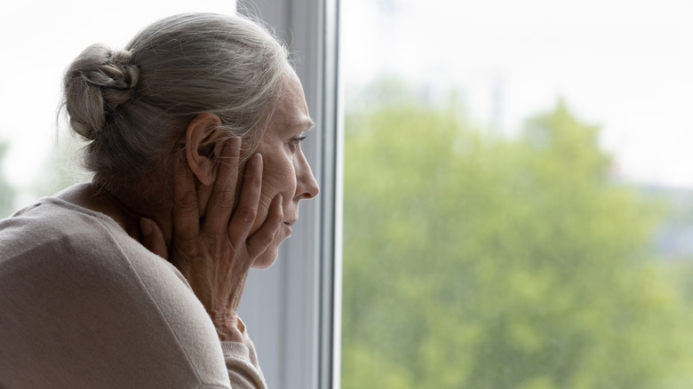 Older woman frowning out window