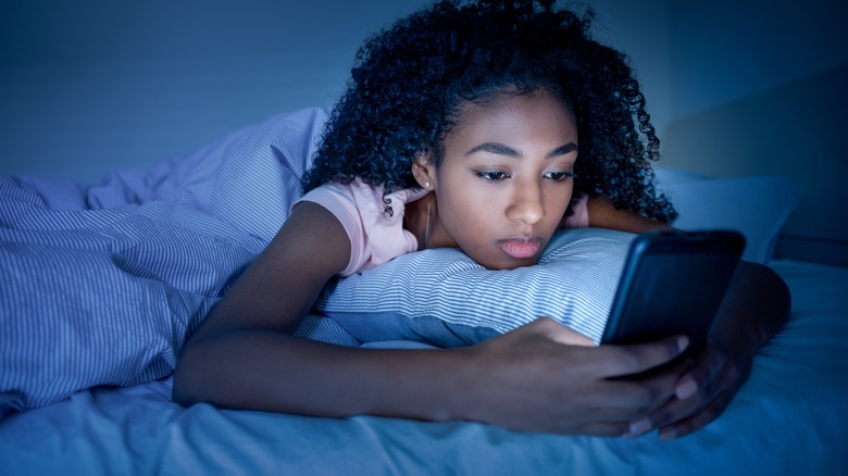 girl using phone in bed