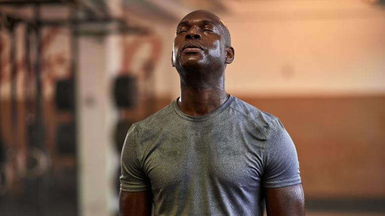 A man wearing a grey T-shirt sweating at the gym 