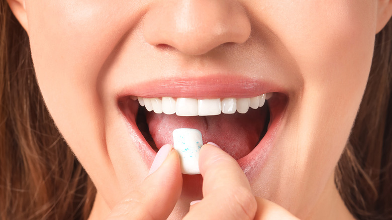 woman putting piece of gum into mouth