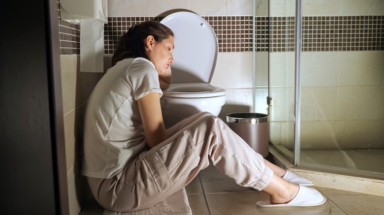 sad woman sitting next to toilet