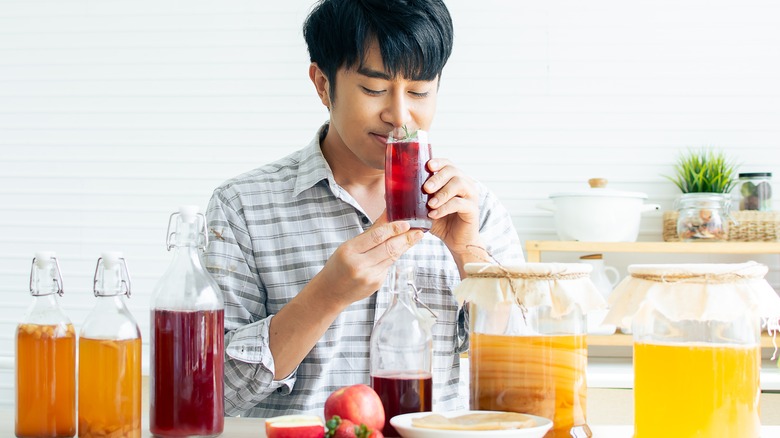 Asian man smiling sipping kombucha