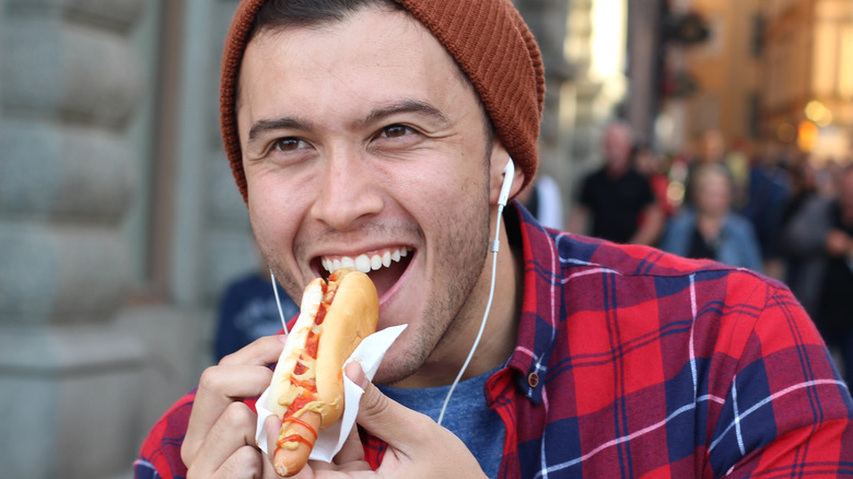 Man eating a hotdog on a busy street