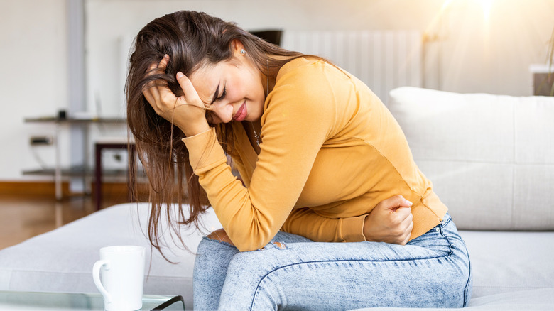 Woman leaning over with arm against stomach