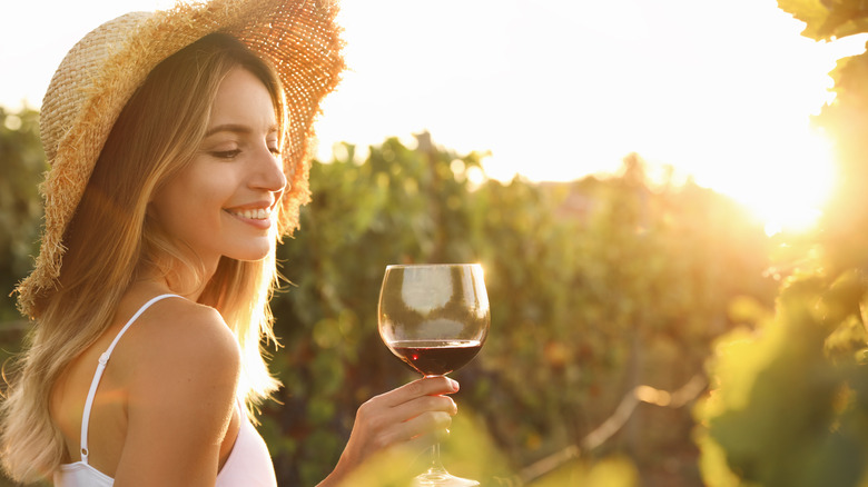 woman with glass of red wine in a vineyard