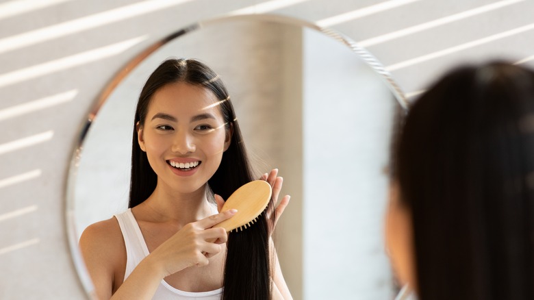 woman brushing hair in mirror 