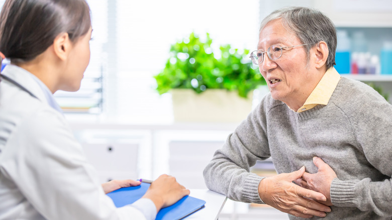 Man holding chest talking to doctor