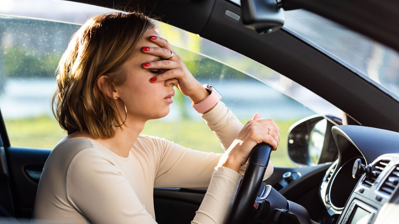 woman in car holding forehead