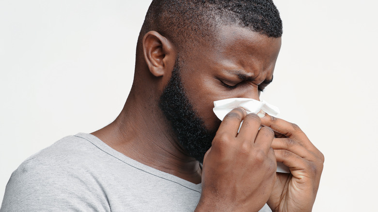 Man blowing nose into tissue