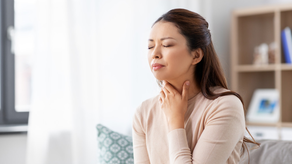 Woman with a cold massaging her throat