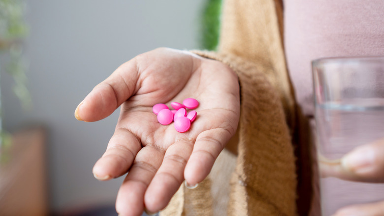 woman's hand holding ibuprofen pills