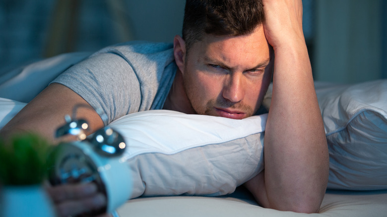 Man in bed looking at clock