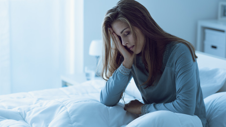 woman sitting in bed holding her head