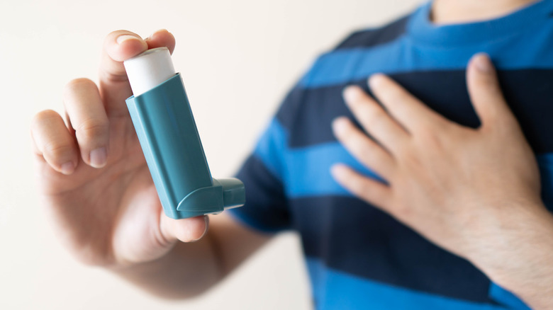 A young man holds an inhaler