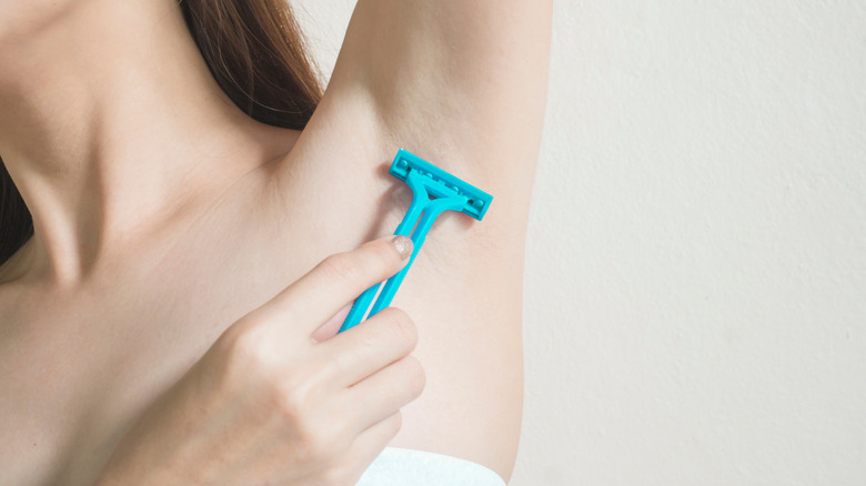 A woman shaves her armpits