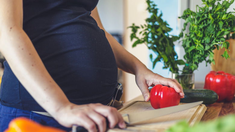 Pregnant person slicing up pepper