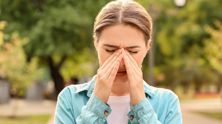 Woman pressing fingers to nose 