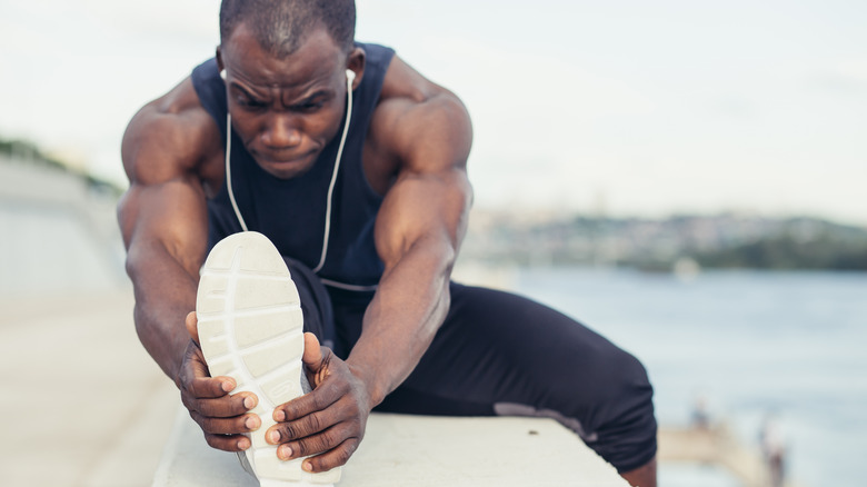 man stretching and holding foot