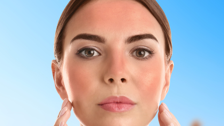 woman touching her sunburnt face