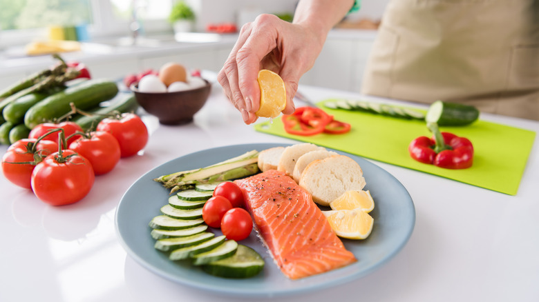 Person squeezing lemon on food plate