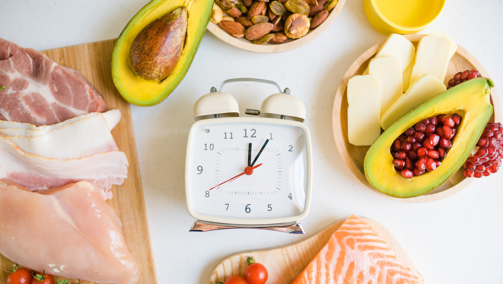 A timer surrounded by raw fish, raw beef, and avocados